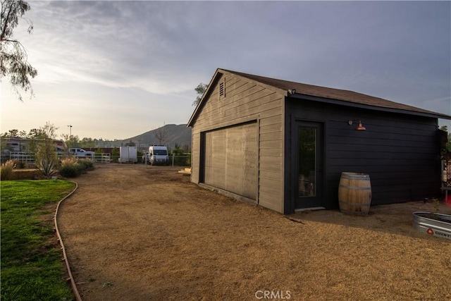 property exterior at dusk with a mountain view, a garage, and an outdoor structure