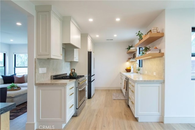 kitchen with stainless steel appliances, tasteful backsplash, sink, and white cabinets