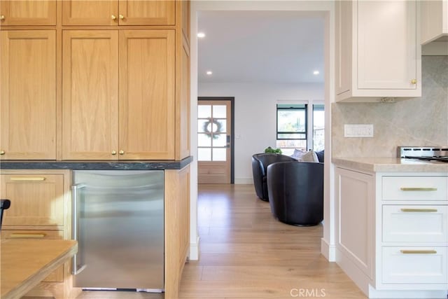 kitchen with tasteful backsplash, built in fridge, light hardwood / wood-style flooring, and white cabinets