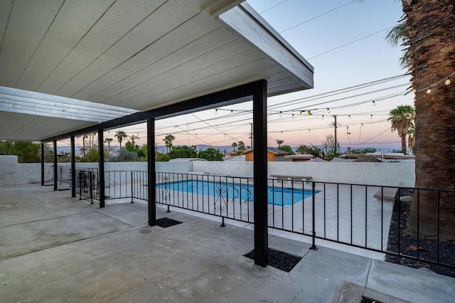 pool at dusk with a patio area