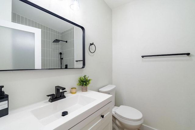 bathroom featuring vanity, toilet, and a tile shower