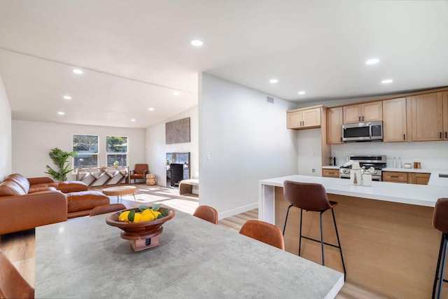 dining space with vaulted ceiling and light hardwood / wood-style flooring