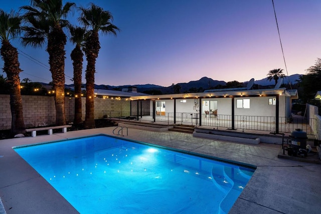 pool at dusk featuring a patio