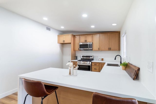 kitchen with stainless steel appliances, sink, a kitchen bar, and kitchen peninsula