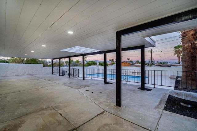 patio terrace at dusk with a fenced in pool