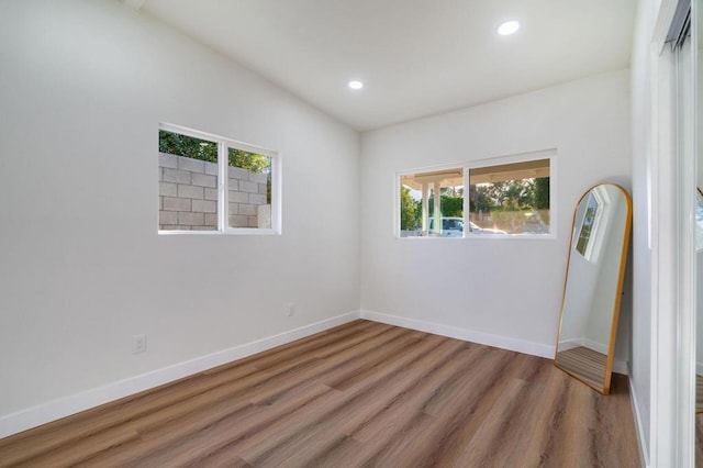 unfurnished room featuring lofted ceiling and hardwood / wood-style floors