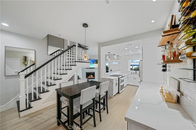 interior space featuring a warm lit fireplace, range with two ovens, light stone countertops, white cabinetry, and pendant lighting