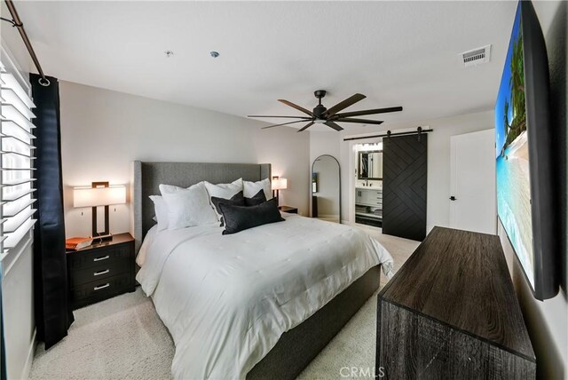 carpeted bedroom with a barn door and ceiling fan