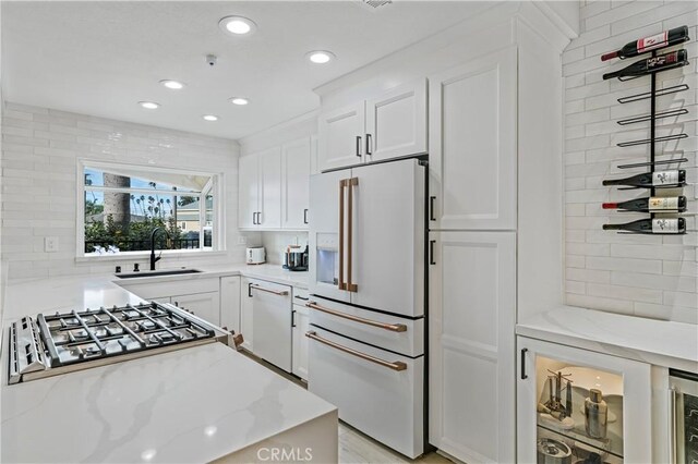 kitchen with sink, light stone counters, tasteful backsplash, white appliances, and white cabinets