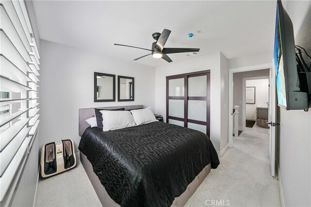 bedroom with multiple windows, ceiling fan, light colored carpet, and ensuite bath