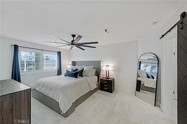 carpeted bedroom featuring ceiling fan, a barn door, and multiple windows