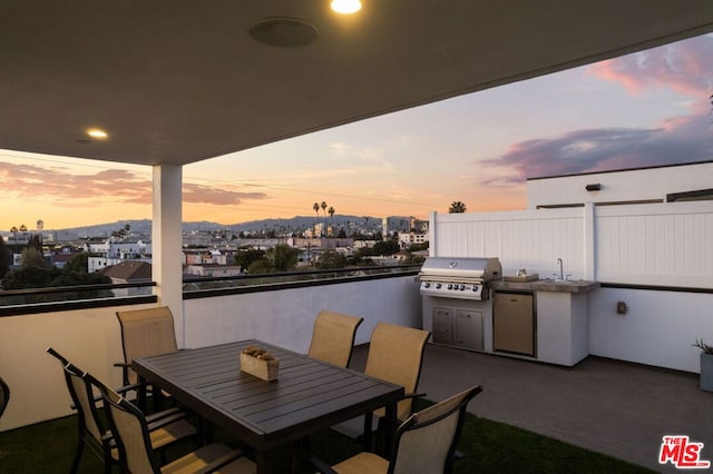 patio terrace at dusk featuring area for grilling, sink, and exterior kitchen