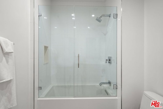 bathroom with toilet and combined bath / shower with glass door