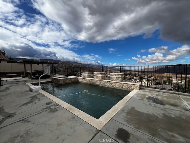 view of swimming pool with a patio, a pool with connected hot tub, fence, and a mountain view