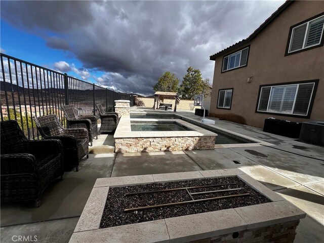 exterior space with central air condition unit, a fenced backyard, and an in ground hot tub