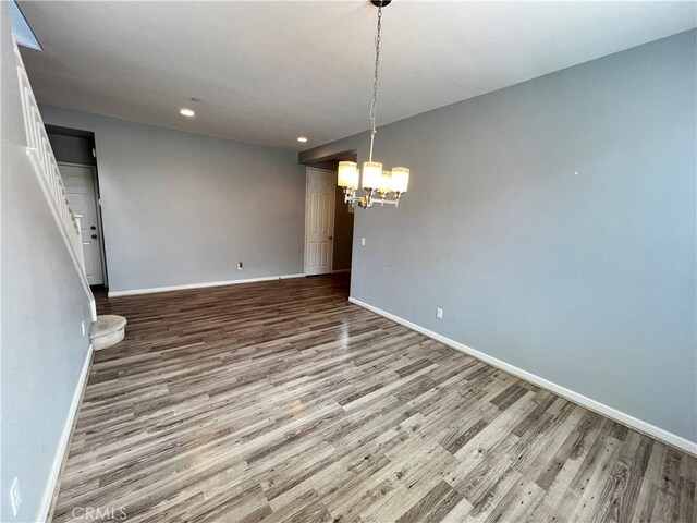 unfurnished dining area featuring baseboards, a chandelier, wood finished floors, and recessed lighting