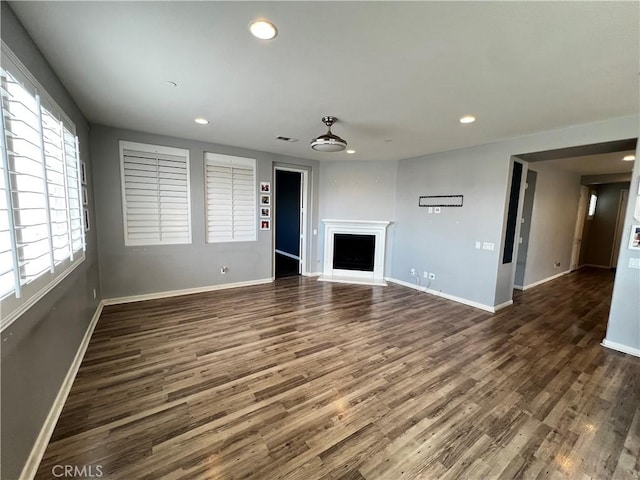 unfurnished living room featuring a fireplace, baseboards, dark wood-style flooring, and recessed lighting