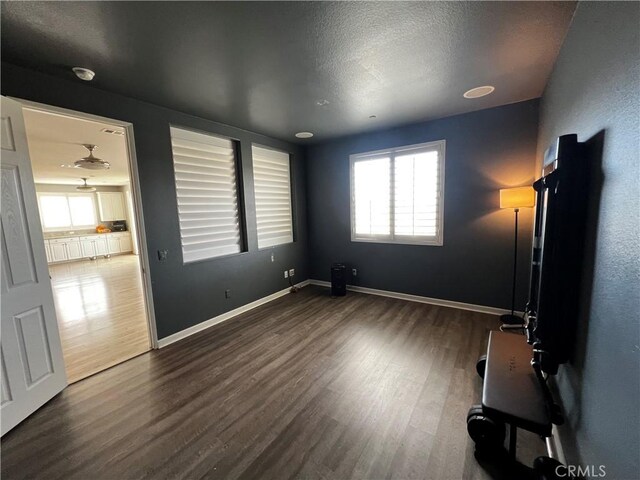 spare room with dark wood-style floors, a textured ceiling, and baseboards