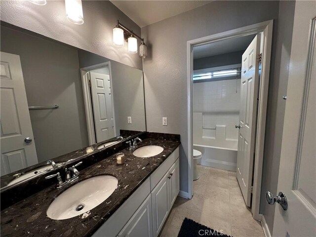 full bathroom featuring double vanity, a sink, toilet, and baseboards