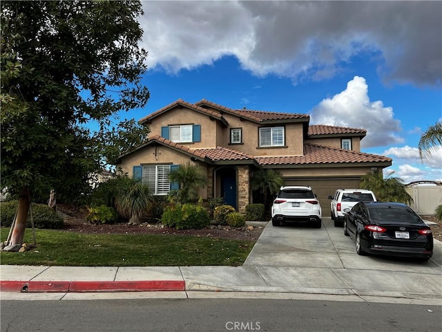 mediterranean / spanish-style house featuring an attached garage, a tile roof, concrete driveway, and stucco siding