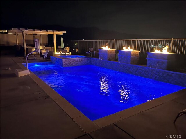 pool at night with a fenced in pool, a fire pit, a patio, and an in ground hot tub