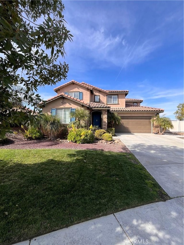 mediterranean / spanish house with a front yard, concrete driveway, a tiled roof, and stucco siding