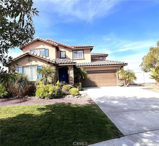 mediterranean / spanish-style house with stucco siding, fence, stone siding, driveway, and a front lawn