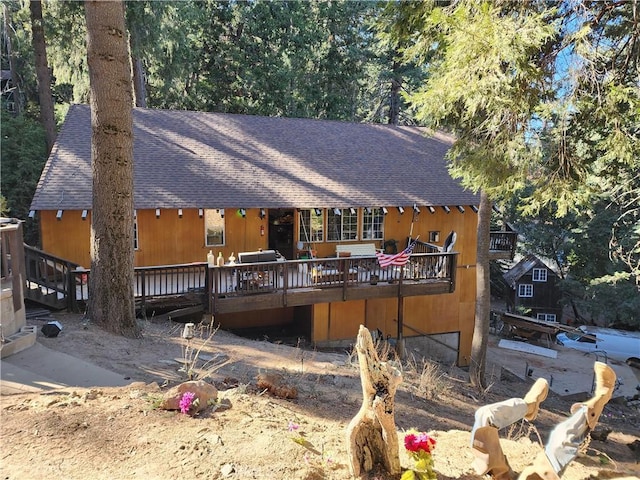 view of front of home with a shingled roof and a wooden deck