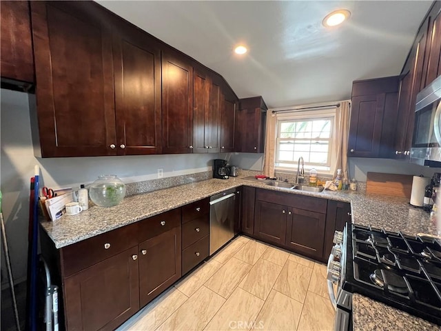 kitchen featuring light stone counters, dark brown cabinetry, appliances with stainless steel finishes, and sink