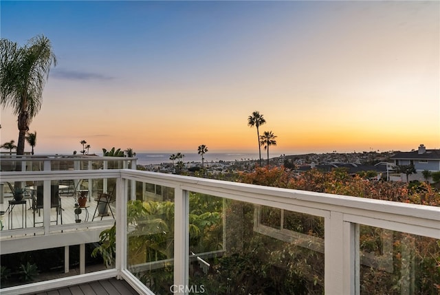 balcony at dusk featuring a water view