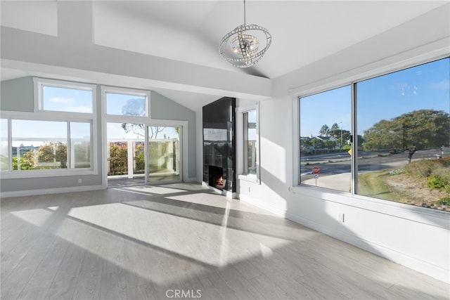 unfurnished sunroom featuring vaulted ceiling, a notable chandelier, and a fireplace