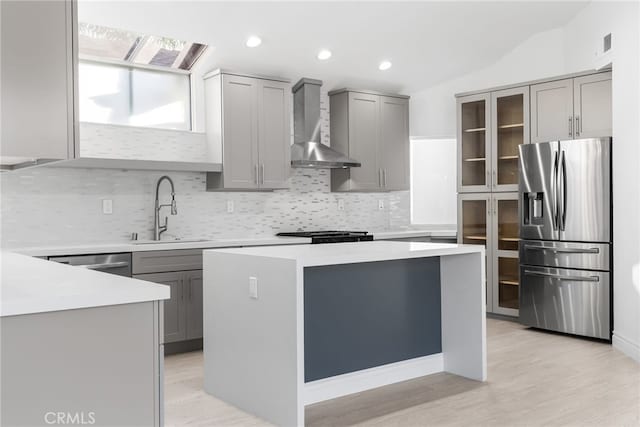 kitchen featuring sink, a kitchen island, wall chimney exhaust hood, and appliances with stainless steel finishes