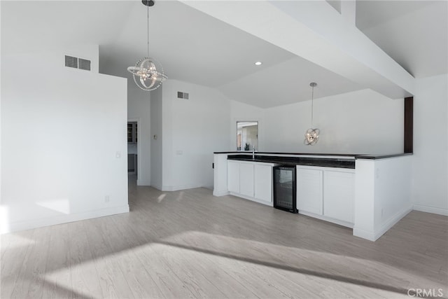 kitchen with white cabinets, pendant lighting, wine cooler, and an inviting chandelier