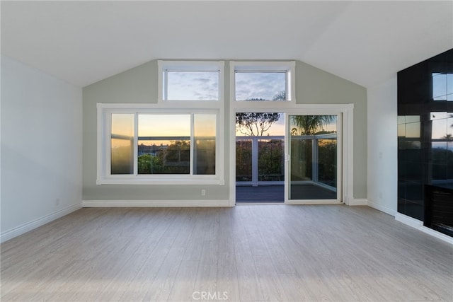 unfurnished living room with vaulted ceiling and light wood-type flooring