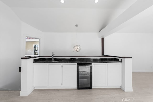 kitchen with pendant lighting, sink, white cabinets, wine cooler, and light hardwood / wood-style floors