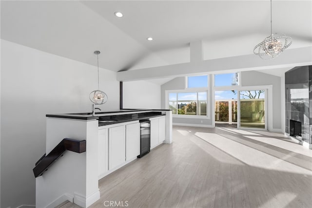 kitchen with vaulted ceiling, wine cooler, white cabinets, and decorative light fixtures