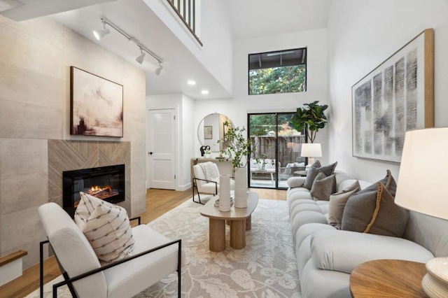 living room featuring light hardwood / wood-style flooring, a fireplace, a high ceiling, and track lighting