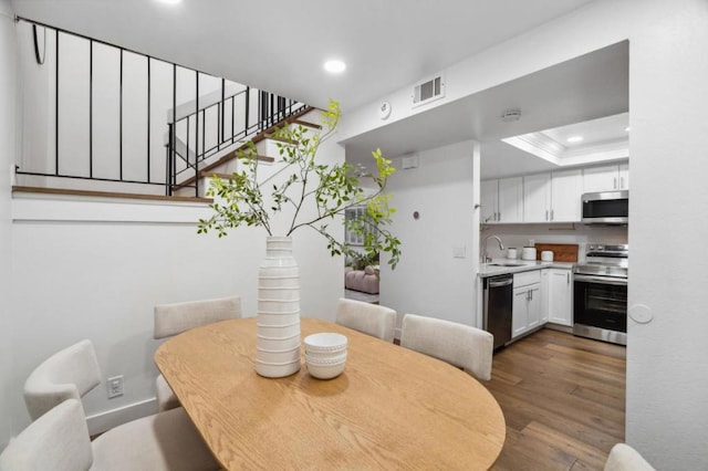 dining space with dark wood-type flooring, sink, and a tray ceiling