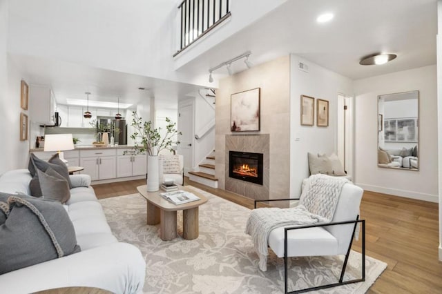 living room with a tiled fireplace, track lighting, and light hardwood / wood-style floors