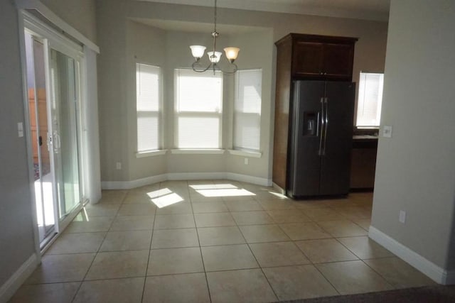 unfurnished dining area with a chandelier and light tile patterned floors