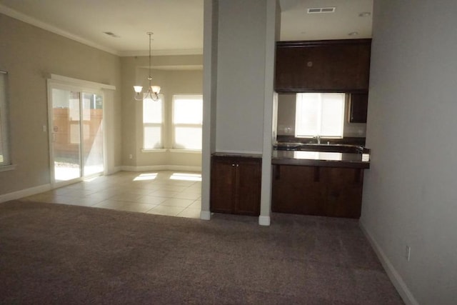 kitchen with dark brown cabinetry, an inviting chandelier, crown molding, carpet flooring, and pendant lighting