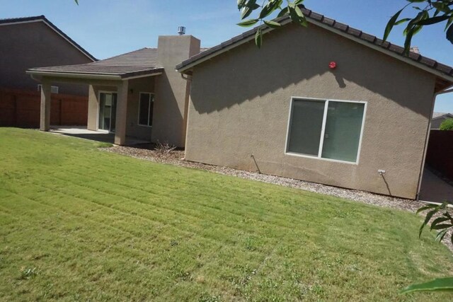 rear view of house with a patio and a lawn