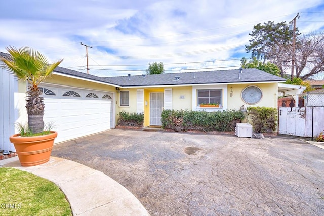 single story home featuring a garage, fence, aphalt driveway, and stucco siding