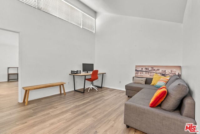 living room with a towering ceiling and light hardwood / wood-style flooring