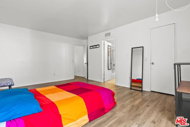 bedroom with ensuite bathroom and light hardwood / wood-style floors