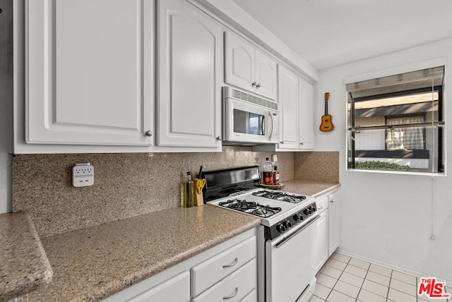 kitchen with tasteful backsplash, light tile patterned flooring, white cabinets, and white appliances