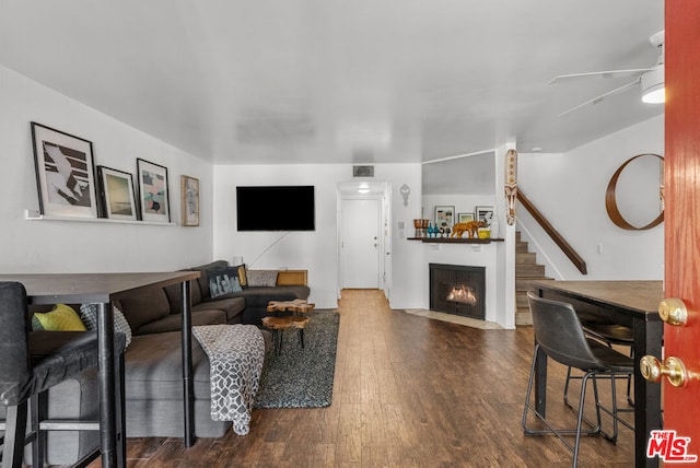 living room featuring ceiling fan and dark hardwood / wood-style flooring