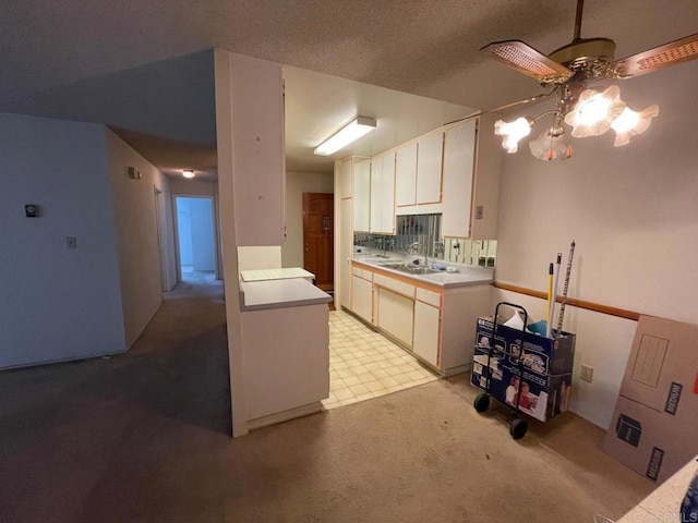 kitchen with white cabinetry, sink, backsplash, and a textured ceiling