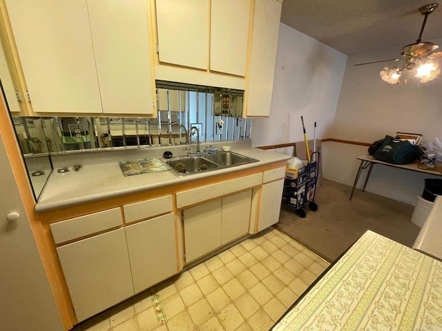 kitchen featuring ceiling fan, sink, a textured ceiling, and decorative light fixtures