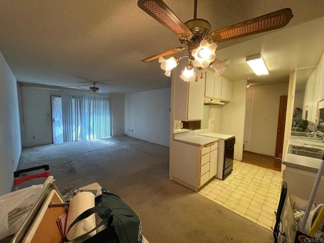 kitchen featuring ceiling fan, range, sink, and white cabinets